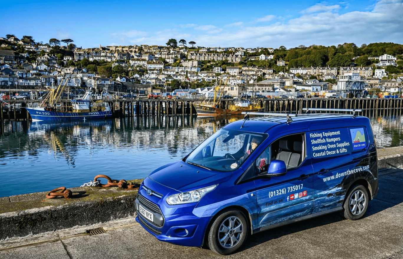 Down The Cove van at coastal harbor with fishing boats